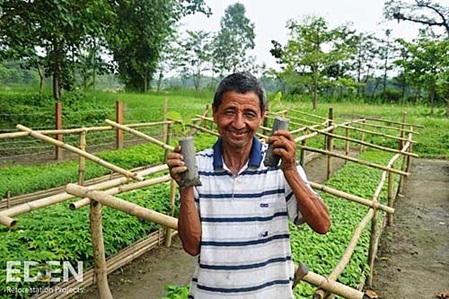 Ein Nepale hält zwei Baumsetzlinge in den Händen
